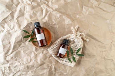 Bej el işi kağıt arka planda üzerinde boş etiketler bulunan bir yüz serumu ya da temel yağ.