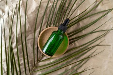 Yeşil bir şişede bej bir el işi kağıdının üzerinde duran bir yüz serumu ya da temel yağ.