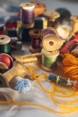 Dikiş aletleri, beyaz masa üzerinde renkli iplikli eski ahşap bobinler, seçici odaklı