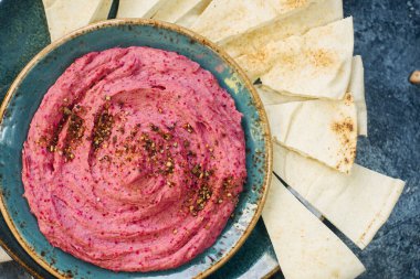 Ev yapımı pancar humusu, nohut ve pide dilimleri koyu taş masada mavi tabakta. Geleneksel orta doğu yemeği, seçici odak, üst görünüm