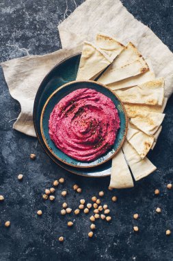 Ev yapımı pancar humusu, nohut ve pide dilimleri koyu taş masada mavi tabakta. Geleneksel orta doğu yemeği, seçici odak, üst görünüm