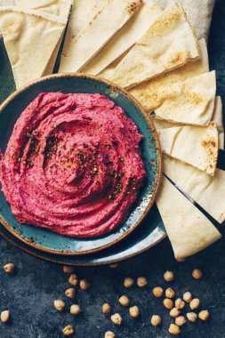 Ev yapımı pancar humusu, nohut ve pide dilimleri koyu taş masada mavi tabakta. Geleneksel orta doğu yemeği, seçici odak, üst görünüm