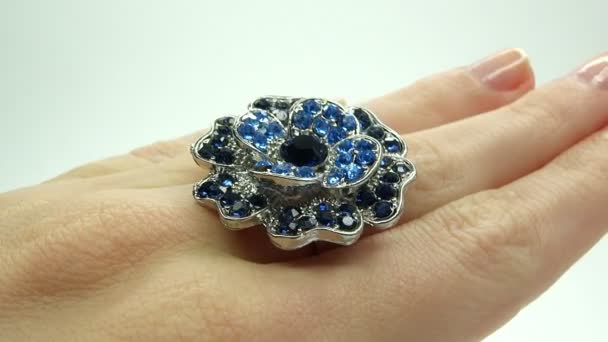 Jewelery ring with blue sapphire crystals putting on the finger — Stock Video