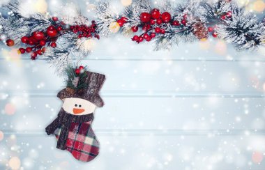 mavi ahşap doku üzerinde noel kardan adam oyuncak kış dalları konileri ve kar                              