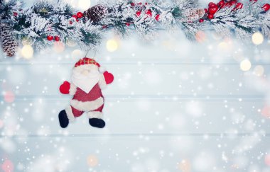 noel santa oyuncak kış dalları koniler ve mavi ahşap doku üzerinde kar                              