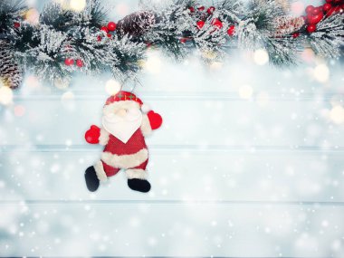 noel santa oyuncak kış dalları koniler ve mavi ahşap doku üzerinde kar                              