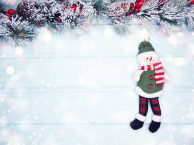 mavi ahşap doku üzerinde noel kardan adam oyuncak kış dalları konileri ve kar                              