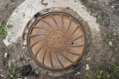 Vladimir, Rusya - 7 Eylül 2021: Şehir caddesinde eski metal rögar kapağı. Çeviri: Devlet Standart ve Kanalizasyon Ağı için kısaltmalar