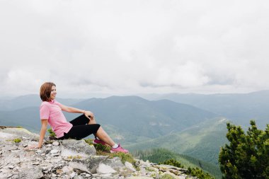 Kız en tepede oturuyor ve Ukrayna 'nın Karpat Dağları' nın güzel manzarasına hayran. Yüksek kalite fotoğraf