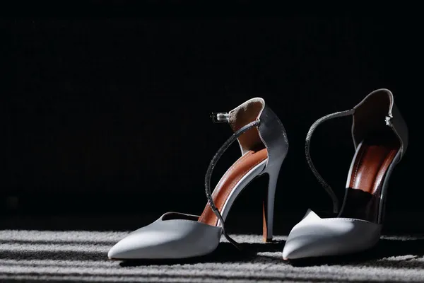 Élégantes chaussures féminines blanches sur un fond sombre — Photo