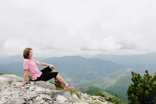 이 소녀는 꼭대기에 앉아 우크라 이나의 카르파티아 산맥의 아름다운 경치를 감상 한다. — 스톡 사진