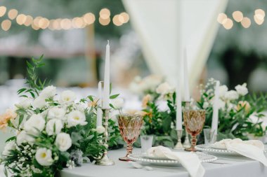  Masa ayarı. Ziyafet masasında peçeteler, kartvizitler, mumlar, bardaklar ve çatal bıçaklarla dolu tabaklar var..