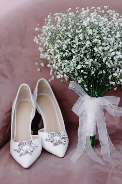 Zusammensetzung eines schönen weißen Hochzeitsstraußes mit einem Paar modischen Hochzeitsschuhen auf rosa Hintergrund — Stockfoto