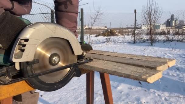 Чоловік розпилює деревину для дому використовуйте на відкритому повітрі взимку — стокове відео