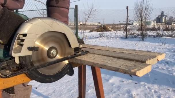 Hombre aserrando madera para uso doméstico al aire libre en invierno — Vídeo de stock