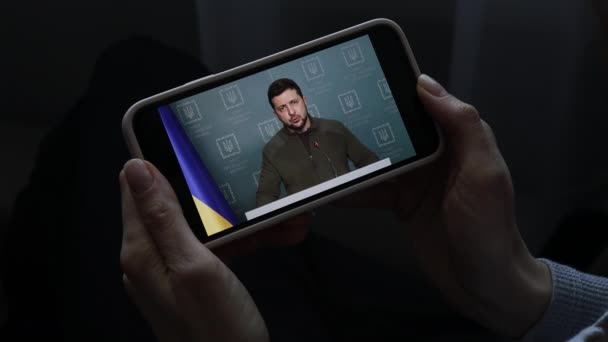 Flicka tittar på tal Ukrainas president Volodymyr Zelensky på smartphone. UKRAINE KYIV - RUARI 2022 — Stockvideo