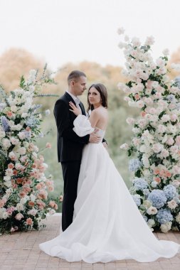  Taze beyaz ve pembe çiçeklerin düğün töreninde güzel gelin ve damat. Açık hava kutlamalarının tasarımı ve organizasyonu. Yüksek kalite fotoğraf
