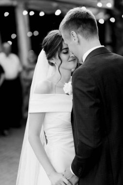 Yeni evlilerin ilk dansı misafirlerin önünde olacak. Siyah beyaz fotoğraf. Yüksek kalite fotoğraf