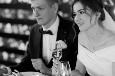 Yeni evliler restoranda bir masada oturup konukları tebrik eder. Siyah beyaz fotoğraf. Yüksek kalite fotoğraf