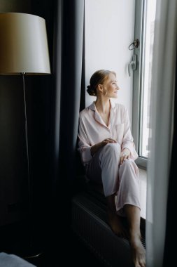 Gelin sabahleyin pencere pervazına oturur ve pencereden dışarı bakar. Yüksek kalite fotoğraf
