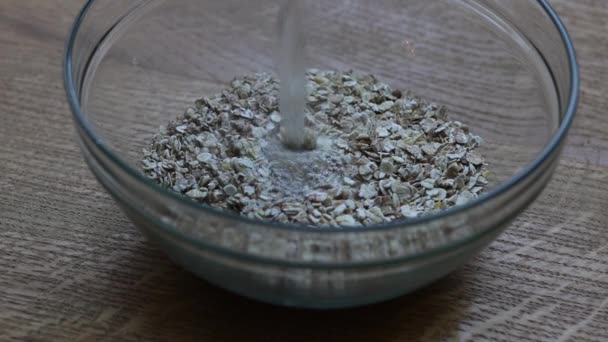 Pours boiling water over oatmeal. Oatmeal and water for breakfast. Close-up — ストック動画