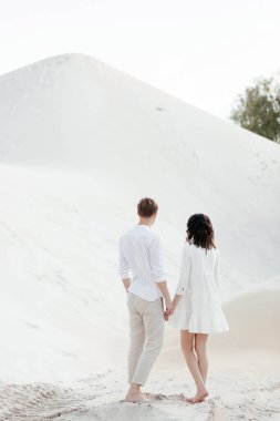 Arkadan kumların üzerinde romantik genç bir çift. Bir erkek bir kadına sarılır. Yüksek kalite fotoğraf