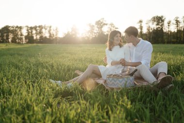 The lovely beautiful couple in love sitting on green grass. Romantic love story in the park. Young girl and boy in love. High quality photo