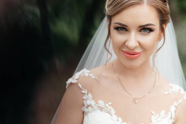  Close-up portrait of a bride dressed in a white dress on a green background. High quality photo