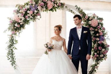 Gelin ve damat düğün töreninde kemerin yanında dururlar. Yüksek kalite fotoğraf