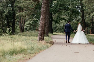  Gelin ve damat bir çam ormanında yürüyorlar ve birbirlerine bakıyorlar. yatay fotoğraf. Yüksek kalite fotoğraf