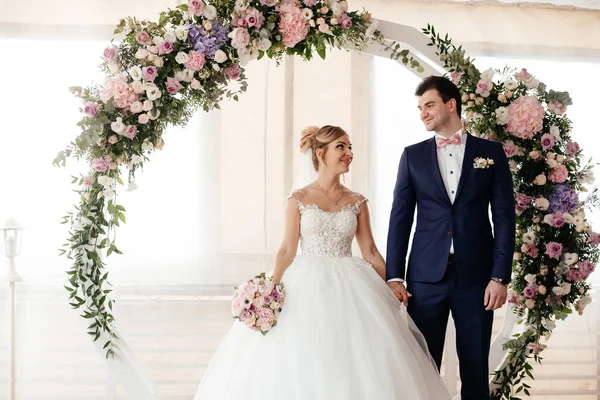 Gelin ve damat düğün töreninde kemerin yanında durur ve birbirlerine bakarlar. Yüksek kalite fotoğraf