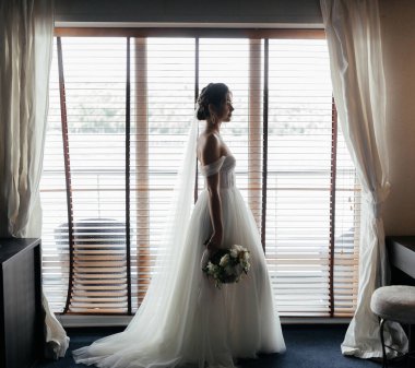 Pencerenin yanında bir buket çiçekli güzel gelin. Yüksek kalite fotoğraf