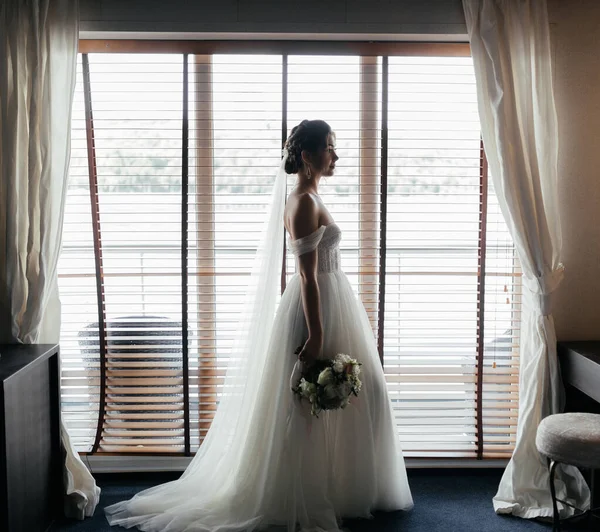 Pencerenin yanında bir buket çiçekli güzel gelin. Yüksek kalite fotoğraf