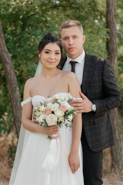  Doğada yeni evlilerin portresi. Yeni evliler kameraya bakar. Yüksek kalite fotoğraf