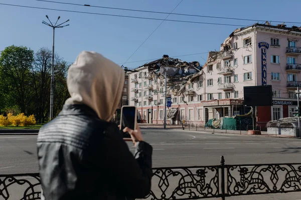 Chernihiv Ukraine 2022: A girl on the phone takes pictures of the destroyed Hotel Ukraine in Chernihiv after an air strike. Ruins during Russias war against Ukraine. — стоковое фото