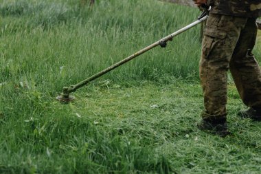 Bir adam çimleri çim biçme makinesiyle biçiyor. Ev tadilatı. Yüksek kalite fotoğraf