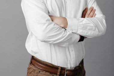 Gri arka planda kolları çapraz duran yakışıklı genç iş adamı. Yüksek kalite fotoğraf