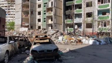 Chernihiv Ukrayna 2022: Bir hava saldırısı sonucu yıkılmış bir binanın arka planında sivil araçlar yakıldı. Rusya Federasyonu ordusunun roket ya da topçu ateşinin sonucu. Savaş.