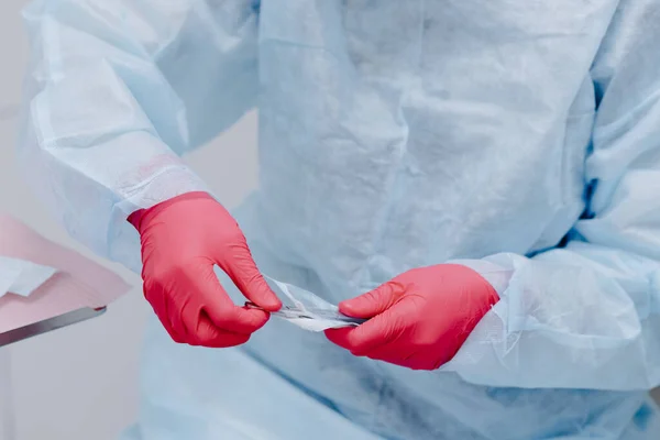 Close up portrait of dentist hands in sterile gloves exposes new tool. Dentist at work. High quality photo