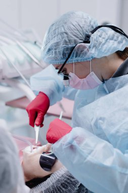 A female dentist with dental instruments cleans her teeth at a dental clinic. Close-up. High quality photo