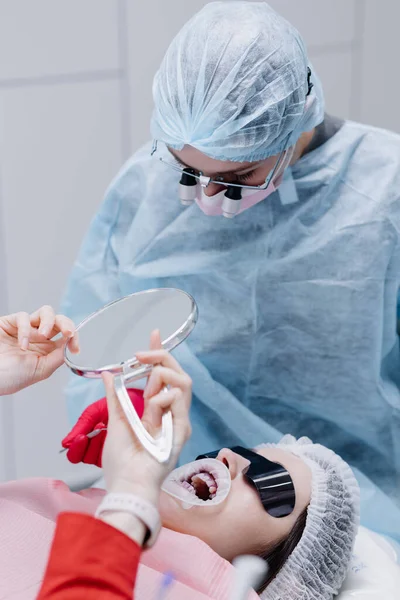 Pacjentka Patrzy Swoje Białe Zęby Lustrze Przed Zabiegiem Siedząc Gabinecie — Zdjęcie stockowe