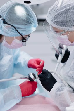  Kadın dişçiler hastanın dişlerini tedavi eder. Yan görüş. Yaklaştın. Dikey fotoğraf. Yüksek kalite fotoğraf