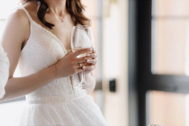 The bride holds a glass of champagne at the banquet. Close-up image. High quality photo