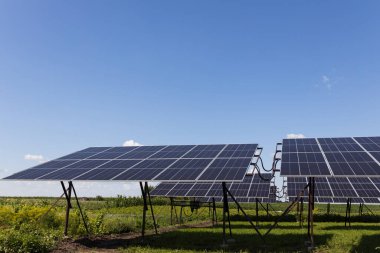  Solar panels in a field lined up against a cloudy blue sky on a sunny day. High quality photo