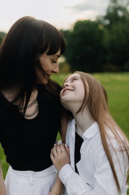 Portrait of mother and little daughter in the park. Mother and daughter look at each other and smile. Happy family concept. High quality photo