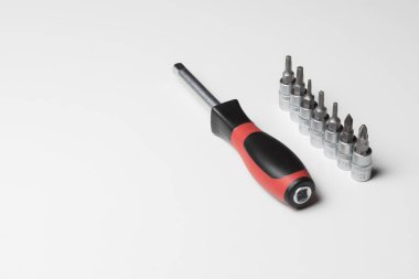 Manual screwdriver with attachments on a white table. A set of attachments for a manual screwdriver. Repair concept. High quality photo