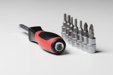  Screwdriver with attachments on the table on a white background. A set of small nozzles. A nozzle for a small screwdriver. High quality photo