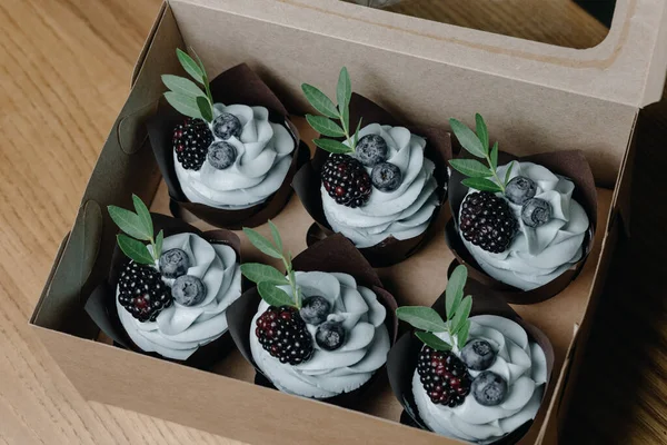 Chocolate cupcakes with fresh berries. Cakes with cream, blueberries and blackberries. Packed in boxes. delicious sweetness. Beautiful pastries. High quality photo