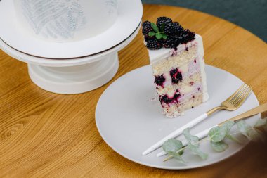 Masasında çatal bıçak olan beyaz bir tabakta böğürtlenli kek. Yüksek kalite fotoğraf