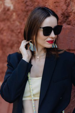 Elinde Ukrayna renginde bir makrome küpe tutan siyah gözlüklü bir esmerin portresi. Yüksek kalite fotoğraf